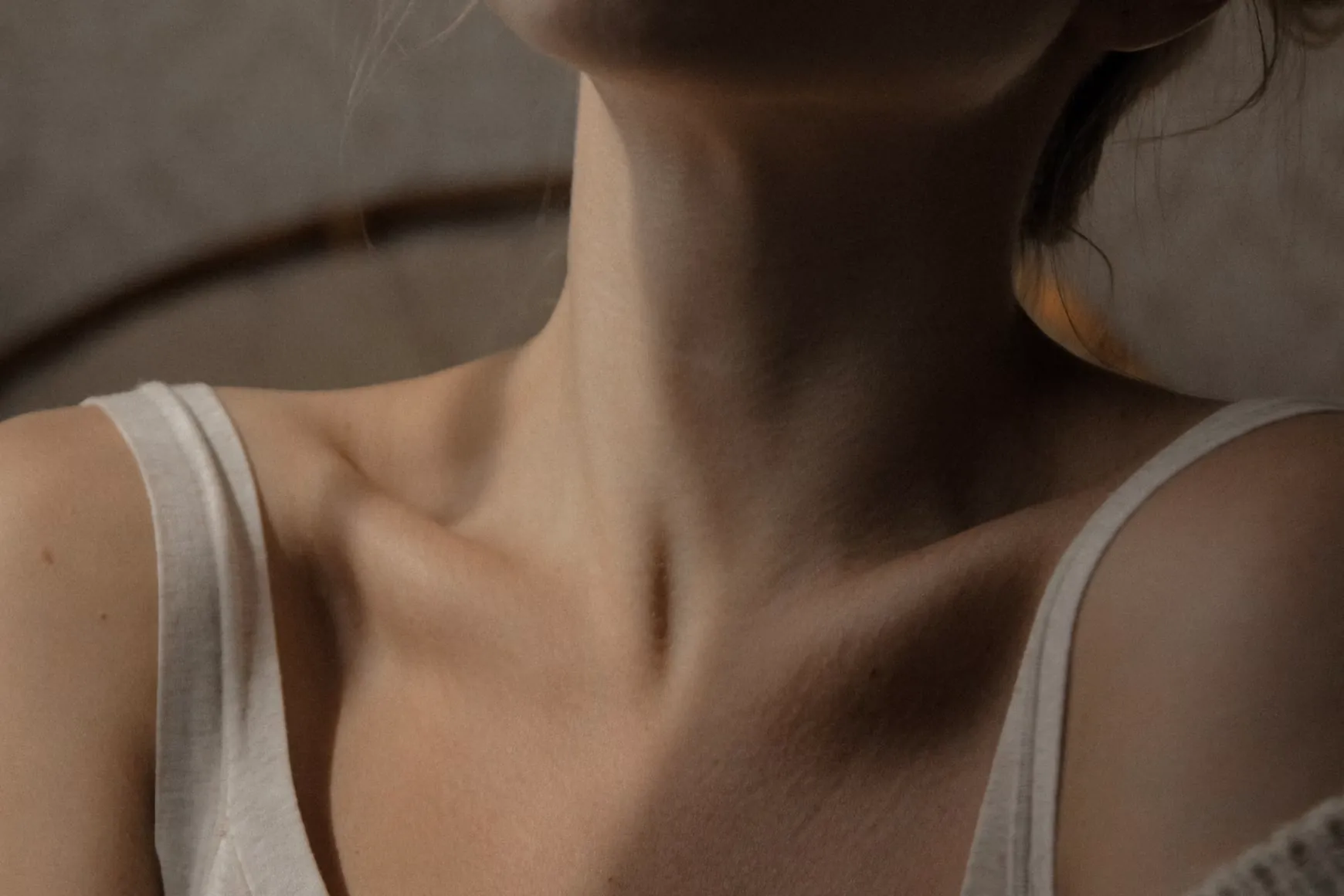 Close-up of a light tank top resting on bare shoulders, collarbone, and neck.